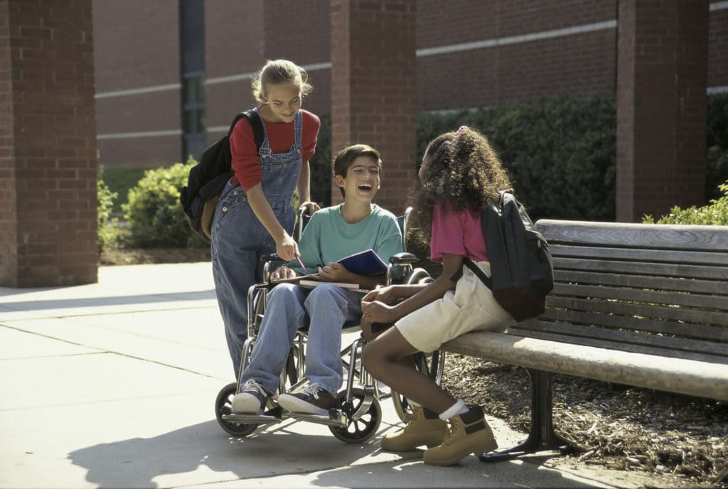 Three children gathered outside on a bench laughing and talking