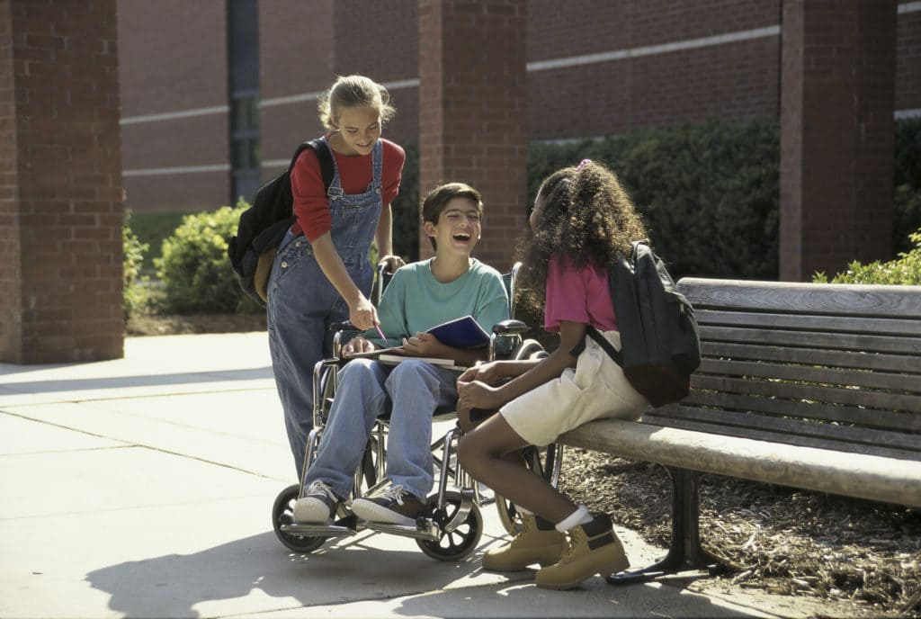 73123118 Three children gathered outside on a bench laughing and talking