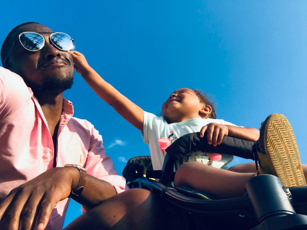 Toddler in a stroller reaches out to man's sunglasses